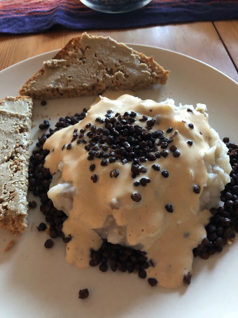 a plate with toast, black lentils, mashed potatoes, and gravy